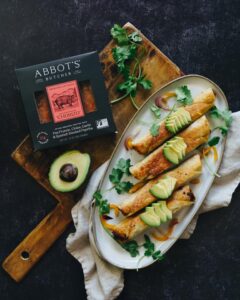 plate of abbots vegan chorizo taquitos garnished with cilantro and avocado