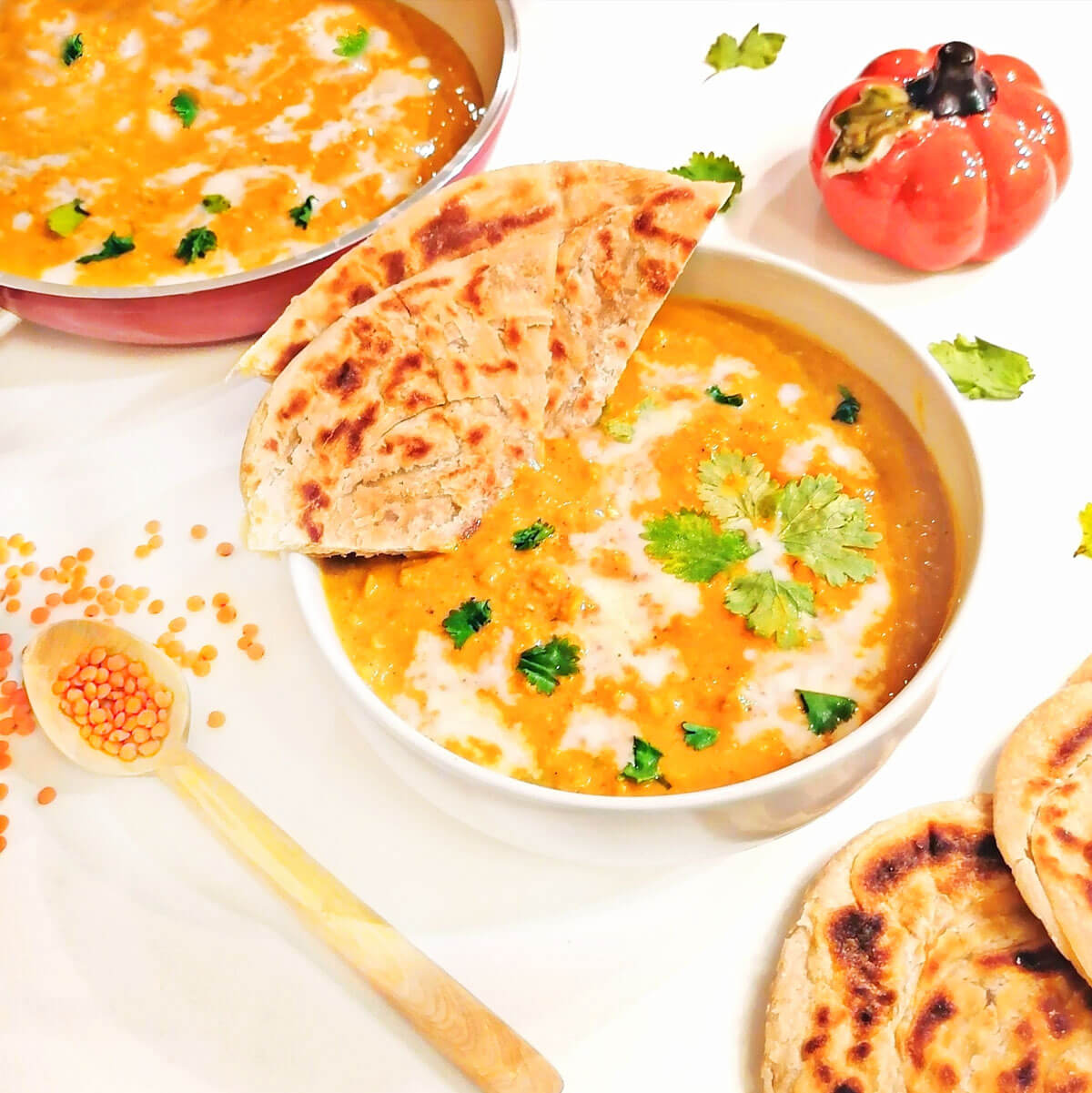 pumpkin lentil soup in bowl with pita bread dipped in