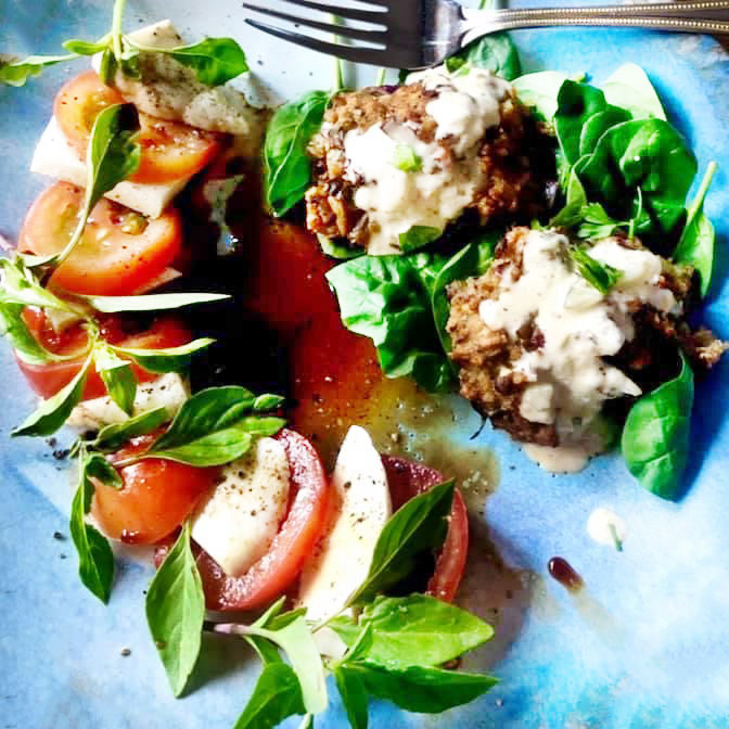 vegan crab cakes with creamy dressing and tomato with basil garnish