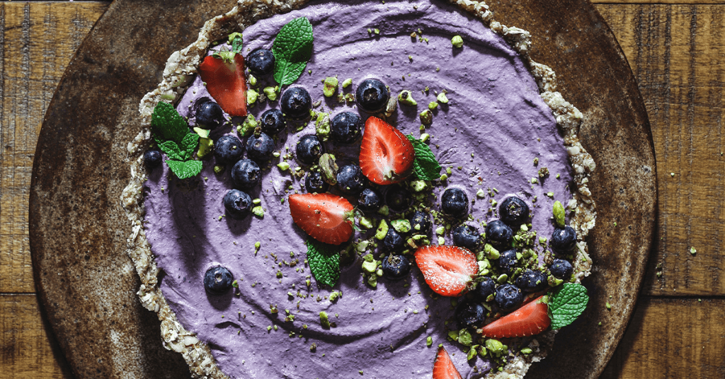 vegan dessert pie with strawberries blueberries and mint crumbled pistachios and violet berry filling