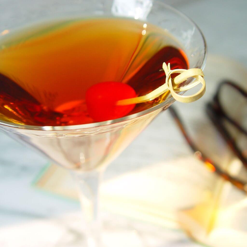 focused image manhattan martini olive on twisted wooden toothpick