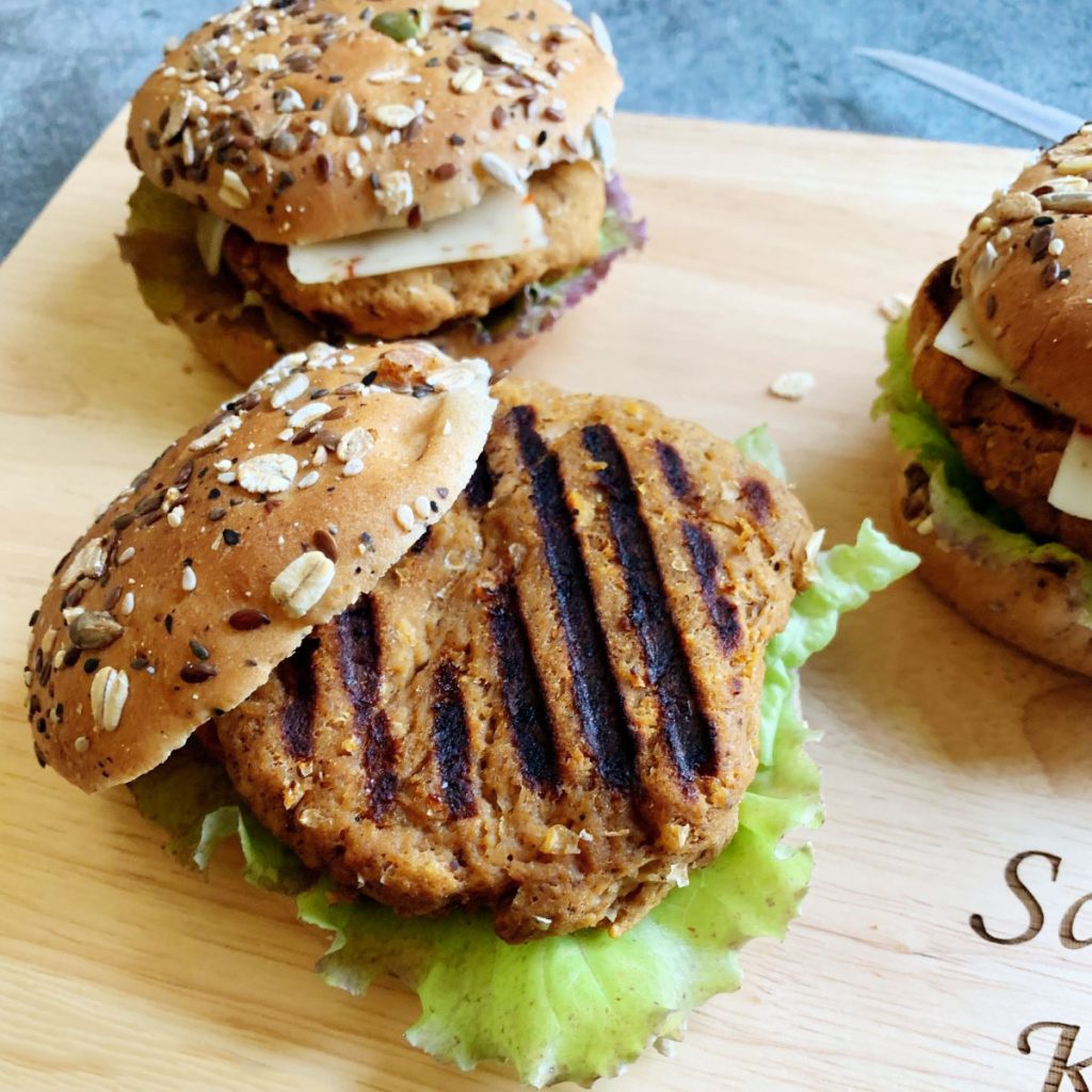three vegan turkey patties on hamburger buns with lettuce and cheese