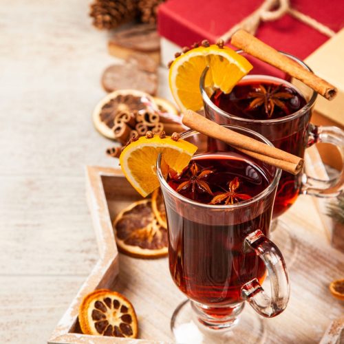 two glasses of mulled wine with orange slices and cinnamon sticks