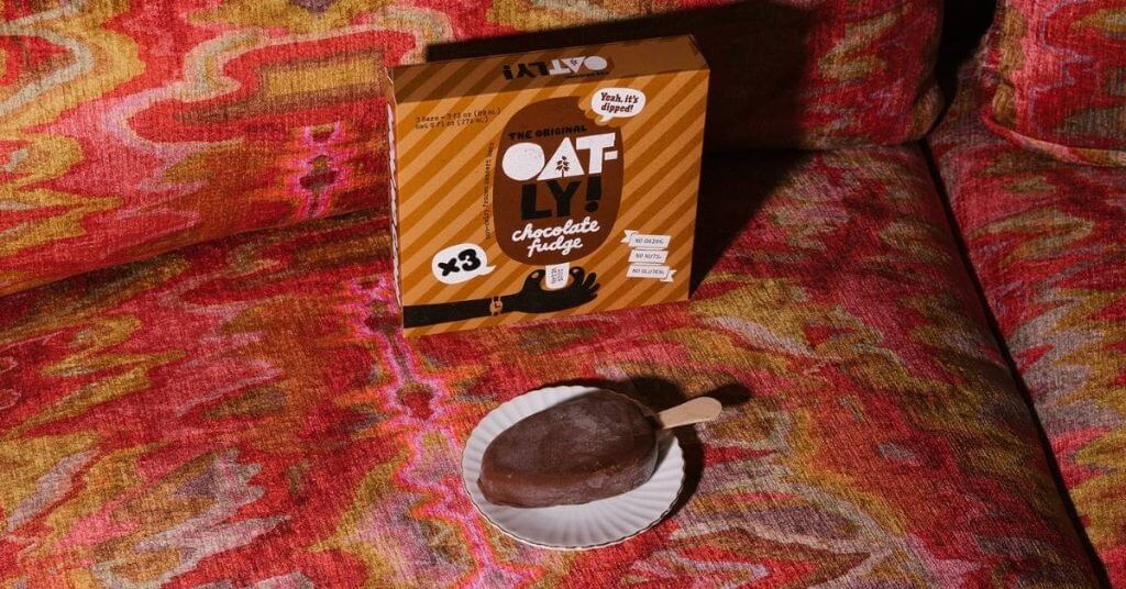 oatly vegan ice cream bar with box on red couch
