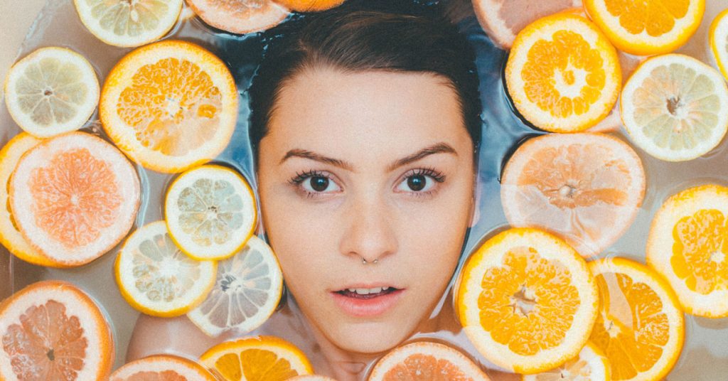 skincare ad womans clear face floats among citrus slices