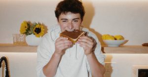 Noah Schnapp eating piece of bread with tbh hazelnut spread
