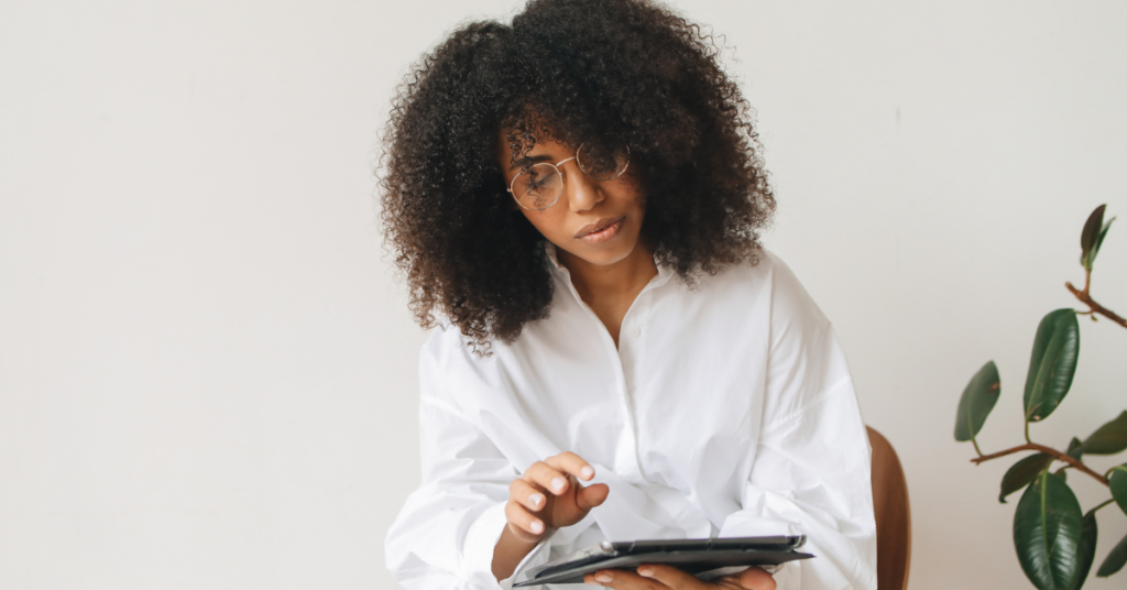 black woman wearing white shirt working on ipad