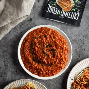 vegan bolognese sauce in a bowl with two plates of spaghetti
