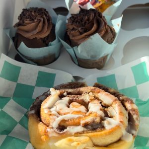 Cinnamon bun and two chocolate cupcakes and one multi color cupcake