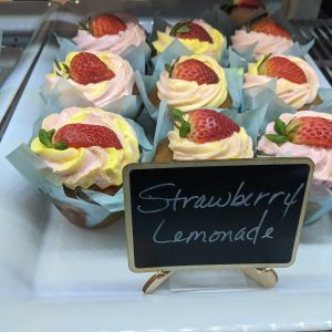 Pink and Yellow Frosted cupcakes with strawberries on top