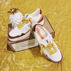 yellow ochre fabric with brown shoe box and white sneakers on top and a pineapple decoration
