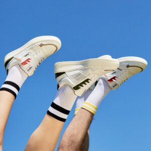 blue sky background with four upside-down legs wearing stripped socks and white sneakers