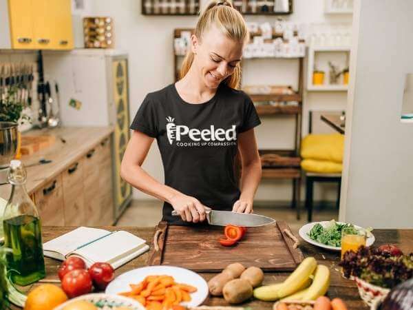 Lady wearing black shirt with "Peeled" Logo slicing tomatoes