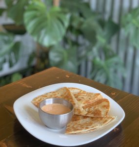 Vegan quesadilla on a plate with a small cup of sauce