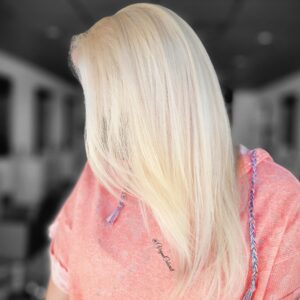 vegan colorist side view of woman with long blonde layered hair peach hoodie