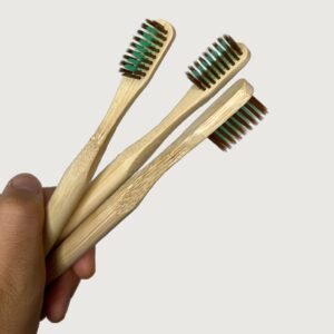 Hand holding up 3 not to die for bamboo toothbrushes