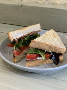 Sandwiches made with tomatoes, leafy greens and vegan mayo on a plate.