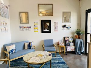 lobby room with medical posters a magazine rack blue cushioned couch and a circular coffee table