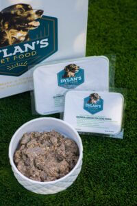 Dylan's Green Pea Dog Food in a bowl in front of containers of same