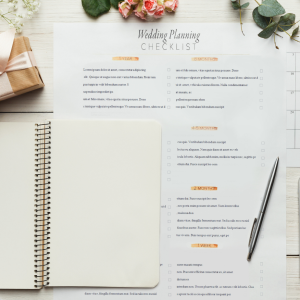 Wedding planning checklist laying on top of a calender page qith wedding rings, pen, smartphone and flower s