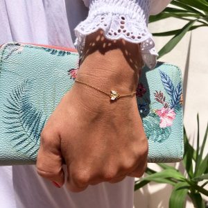 Hurtig Lane jewelry around wrist with hand clutching blue wallet